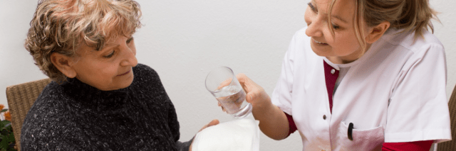 Eine Frau erklärt einer anderen eine Inkontinenzhilfe, die sie in der Hand hält.